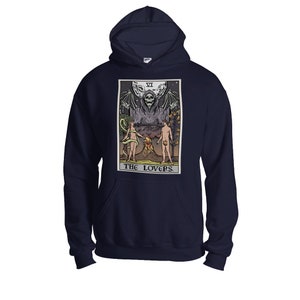 Puede incluir: Sudadera con capucha azul marino con un gr&aacute;fico de la carta del tarot de Los Enamorados. La carta presenta una figura esquel&eacute;tica con alas extendidas, dos figuras desnudas y el texto "The Lovers" en la parte inferior.
