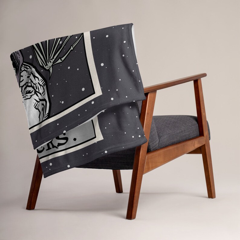 May include: A dark gray fleece throw blanket with a white border and a black and white illustration of a creature with a star-filled background. The text "Shroom Queens" is visible in the bottom corner of the illustration.