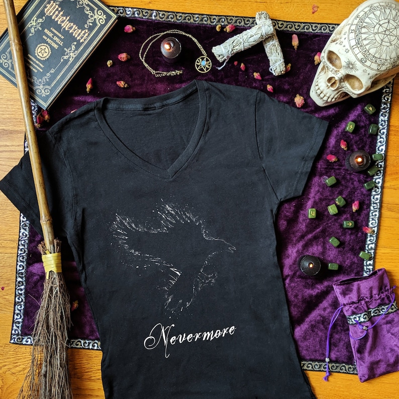 May include: Black v-neck t-shirt with a white silhouette of a raven and the text "Nevermore" printed on the front.