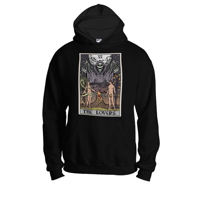Puede incluir: Sudadera con capucha negra con un estampado gr&aacute;fico de una carta del tarot que representa a Los Amantes. La carta muestra una figura esquel&eacute;tica con los brazos extendidos, dos figuras desnudas y el texto "THE LOVERS" en la parte inferior.