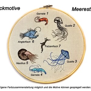 May include: Embroidered hoop art featuring sea creatures, including a blue anglerfish, a brown nautilus, a seahorse, and three jellyfish. The hoop is labeled "Stickmotive" and "Meerestiere" in German.