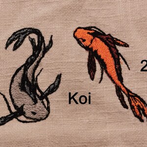 May include: Two embroidered koi fish on a beige fabric background. The fish are numbered 1 and 2. The word "Koi" is embroidered below the fish.