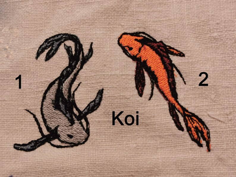 May include: Two embroidered koi fish on a beige fabric background. The fish are numbered 1 and 2. The word "Koi" is embroidered below the fish.