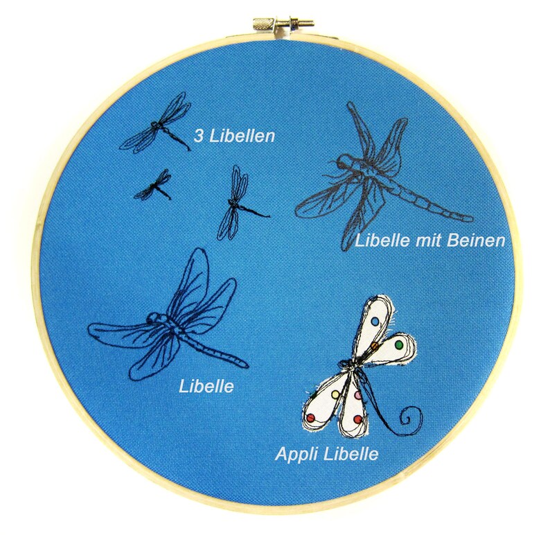 May include: A blue embroidery hoop with four black embroidered dragonflies and one colorful appliqu&eacute; dragonfly. The text "3 Libellen", "Libelle mit Beinen", "Libelle", and "Appli Libelle" is embroidered on the hoop.