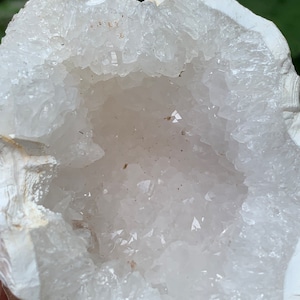 May include: A white geode with a large opening revealing a cluster of white crystals.