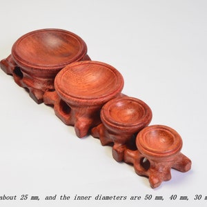 Op de afbeelding: Vijf houten display stands in verschillende maten, vari&euml;rend van 20 mm tot 50 mm in diameter. De stands zijn gemaakt van rood hout en hebben een gladde, gepolijste afwerking.