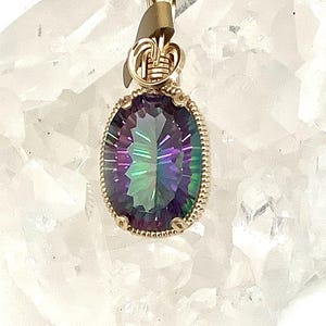 May include: A gold wire wrapped pendant featuring a large oval-shaped iridescent gemstone with a rainbow of colors, including purple, green, and blue.