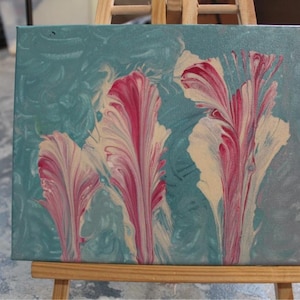 Puede incluir: Pintura abstracta sobre lienzo con tres remolinos de color rosa, blanco y crema sobre un fondo azul verdoso.