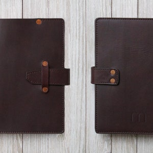 May include: Two brown leather journals with gold accents and a strap closure. The journal on the right has the initials "CC" embossed on the front.