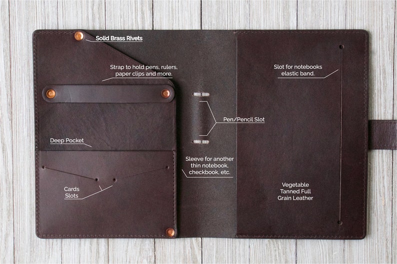 May include: A brown leather notebook cover with multiple pockets and slots. It features a strap to hold pens, rulers, and paper clips. The cover is made of vegetable tanned full grain leather and has solid brass rivets. The text "Solid Brass Rivets" is printed on the cover.
