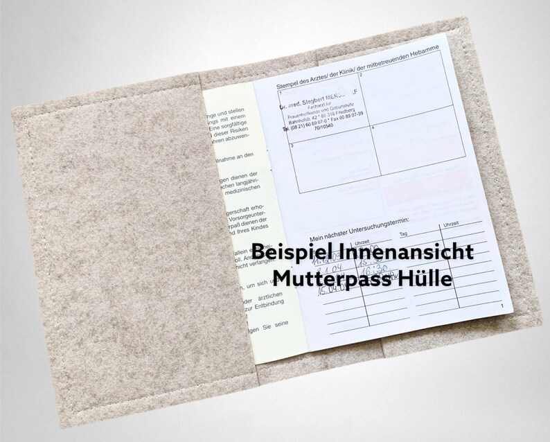 May include: A light grey felt Mutterpass cover, open to show the inside. The cover contains a document with printed text and handwritten notes. The text "Beispiel Innenansicht Mutterpass H&uuml;lle" is visible on the cover.