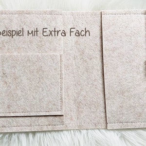 May include: A beige felt organizer with a pocket and a string closure with wooden beads. The text "Beispiel mit Extra Fach" is printed on the felt. The organizer is designed to hold items.