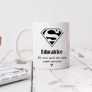 May include: White ceramic mug with a black Superman logo and the text "Educatrice Et vous quel est votre super pouvoir?"