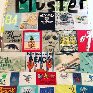 May include: A patchwork quilt composed of t-shirts with assorted designs and text. Graphics include a lion, a pineapple wearing sunglasses, and the word "Muster". The quilt displays a range of colours and styles, with a variety of measurements.