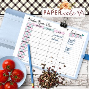 Op de afbeelding: Een wekelijkse maaltijdplanner met een roze en blauw geruit ontwerp. De planner heeft secties voor ontbijt, lunch, diner en een boodschappenlijst. De boodschappenlijst bevat items zoals mozzarella, basilicum, olijfolie, baguette, boter en specerijen.