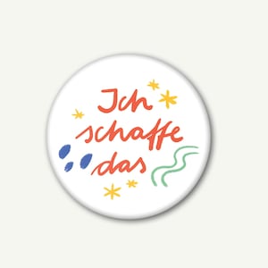 Könnte beinhalten: Ein weißer runder Knopf mit dem Text "Ich schaffe das" in Rot, umgeben von blauen und grünen abstrakten Formen und gelben Sternen.
