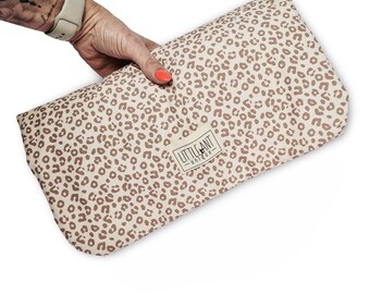 May include: A beige and brown leopard print changing mat with the text "Little Ant - unique" in a white rectangle.