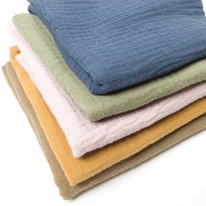 May include: A stack of five fabric cloths in different colors, including blue, green, pink, yellow, and brown. The cloths are folded and stacked on top of each other.