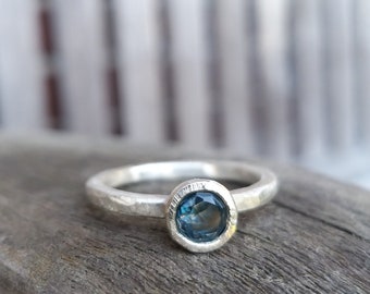 Silver engagement ring with dark blue topaz