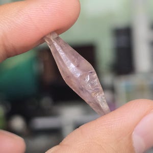 Op de afbeelding: Een heldere, gefacetteerde, paarse kristallen punt met een puntige punt.