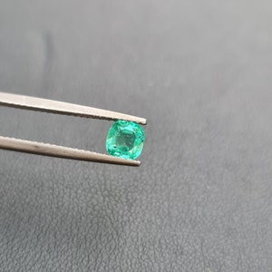 Puede incluir: Una gema de esmeralda verde vibrante sostenida en pinzas. La esmeralda tiene un corte coj&iacute;n y es de un hermoso tono verde.
