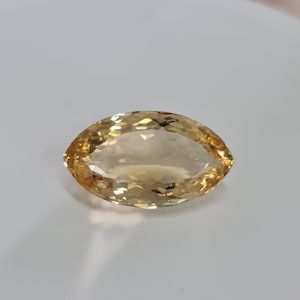 May include: A golden yellow gemstone with a faceted oval shape.
