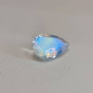 May include: A pear-shaped iridescent gemstone with a blue and white color.