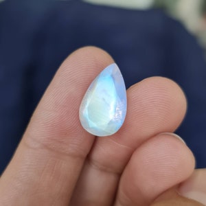 May include: A teardrop-shaped moonstone gemstone with a pearlescent sheen and iridescent rainbow colors.