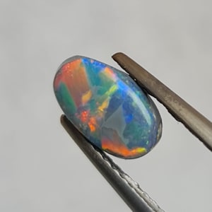 Natural Australian colorful black Opal, 0.91ct. Perfect for pendants and rings! lively play of color and elegant flat oval shape. CD788