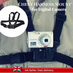 May include: Black chest harness mount for a digital camera. The harness has adjustable straps and a quick release buckle. The camera is attached to the harness with a mount.