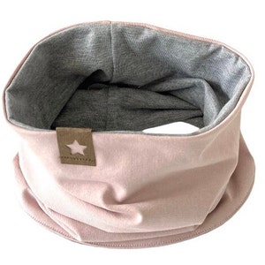 Könnte beinhalten: Ein rosa-grauer, reversibler Halsschoner mit einem braunen sternförmigen Patch.