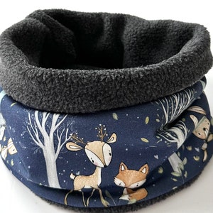 Könnte beinhalten: Ein marineblauer und grauer Fleece-Schlauchschal mit einem Waldtiermotiv. Der Druck zeigt ein Reh und einen Fuchs mit Bäumen und Blättern. Das Innenfutter ist aus weichem, dunkelgrauem Fleece. Dieser kuschelige Schal ist für Wärme und Komfort konzipiert.