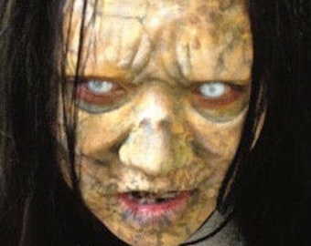 May include: Close-up of a pale, weathered face with white eyes and a wide, open mouth. The face is covered in cracks and lines, giving it a creepy and unsettling appearance.