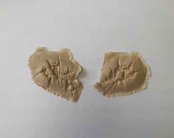 Peut inclure: Deux patchs de tissu beige avec un motif texturé en relief. Le tissu est effiloché sur les bords.