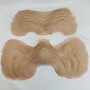 May include: Two beige silicone molds for creating a realistic-looking animal nose. The molds are detailed with textured lines and a small hole for nostrils.
