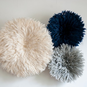 Puede incluir: Tres decoraciones de pared redondas hechas de plumas. La decoración más grande es blanca, la decoración del medio es gris y la más pequeña es azul oscuro.