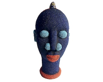 May include: A blue beaded sculpture of a human head with turquoise eyes and a red mouth.
