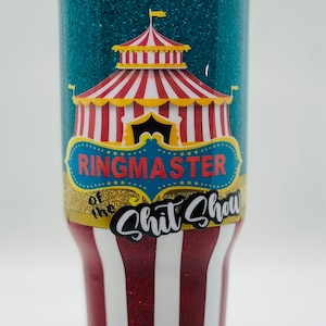May include: A teal glitter tumbler with a red and white striped circus tent graphic. The text "Ringmaster of the Shit Show" is printed on the tumbler.