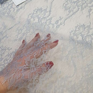 May include: Light blue lace fabric with a delicate floral pattern. The fabric is soft and sheer, and it would be perfect for a variety of projects, such as dresses, skirts, and tops.