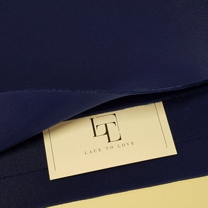 May include: A close-up of a dark blue fabric with a white tag that says "Lace to Love" in a stylized font.