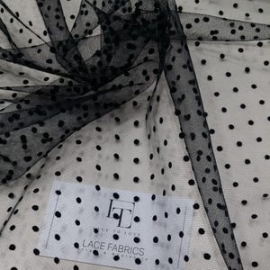 Peut inclure: Tissu de tulle noir avec des pois en velours noir. Le tissu est transparent et a un toucher doux et délicat. Les pois sont espacés uniformément et ajoutent une touche d'élégance au tissu.