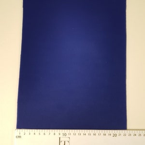 May include: A solid blue piece of fabric measuring 25 cm by 20 cm. The fabric is laid flat on a white surface with a ruler underneath.