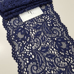 May include: Navy blue lace trim with a floral pattern. The lace is delicate and intricate, with a scalloped edge.