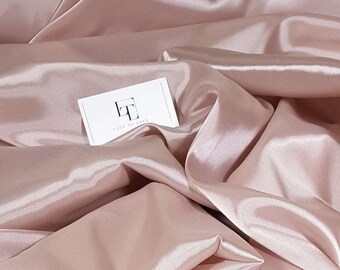 Puede incluir: Primer plano de una tela de satén rosa pálido con una tarjeta de visita blanca que dice "Lace to Love" en texto negro.