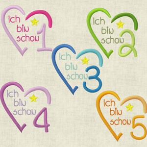 Könnte beinhalten: Fünf gestickte Herzen mit dem Text "Ich bin schow" und einer Zahl von 1 bis 5. Jedes Herz hat eine andere Farbe: rosa, grün, blau, lila und orange.