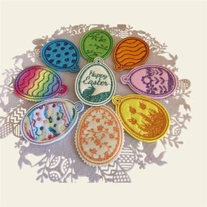 Puede incluir: Nueve adornos de huevos de Pascua de fieltro con varios diseños, que incluyen un arcoíris, lunares, flores y un conejito. Un adorno dice "Feliz Pascua".