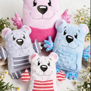 May include: Four plush bear toys in pink, light blue, gray, and white. Each bear features a textured minky fabric body, embroidered facial details, and patterned fabric accents on the ears, hands, and feet. The bears have striped or solid bellies.