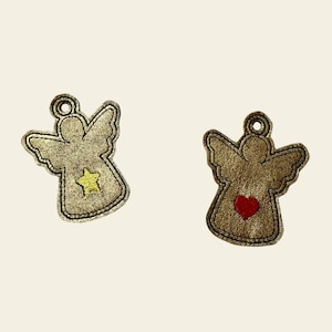 Puede incluir: Dos adornos de ángel dorados con detalles bordados. Un ángel tiene una estrella amarilla y el otro un corazón rojo.