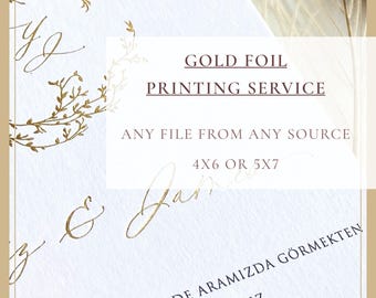 May include: A white card with gold foil lettering and a botanical wreath design. The text reads: GOLD FOIL PRINTING SERVICE, ANY FILE FROM ANY SOURCE, 4X6 OR 5X7, and Turkish text including GÖRMEKTEN, BÜYÜK MUTLULUK DUYARIZ, ÇİÇEK AİLELERİ, SAAT 19.