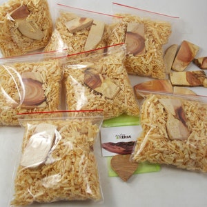 Könnte beinhalten: Mehrere durchsichtige Plastiktüten gefüllt mit Holzspänen und Holzstücken. Die Beutel sind mit "natur KERBE" beschriftet.